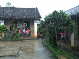 暴雨中，教室里出現漏水情況，學生們在屋檐下避雨